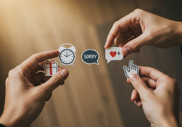 Hands crafting an apology with symbols of five love languages